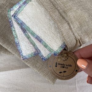 Reusable makeup remover pads made by Equilibrium Lifestyle and a woman holding the product tag