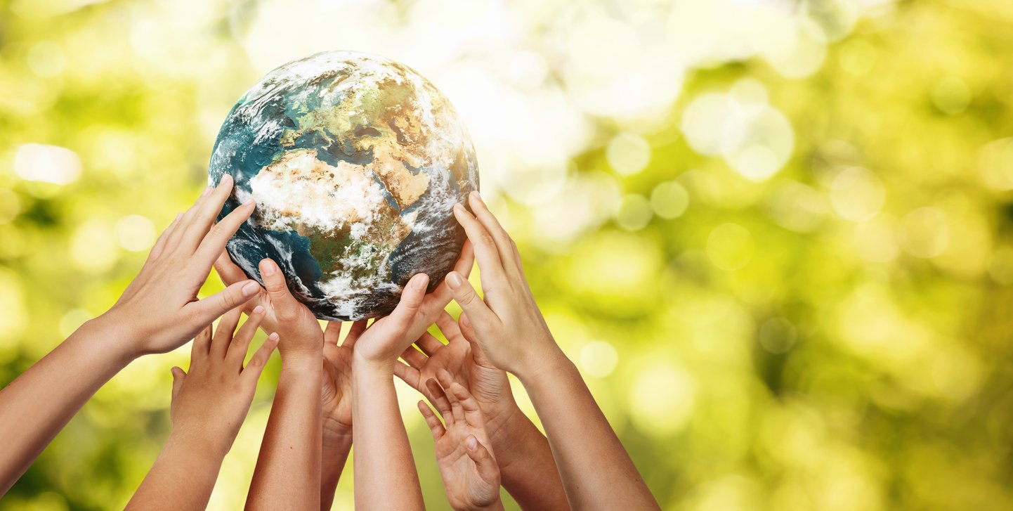 People holding up a world globe to promote sustainability in order to encourage a greener lifestyle with trees in the background