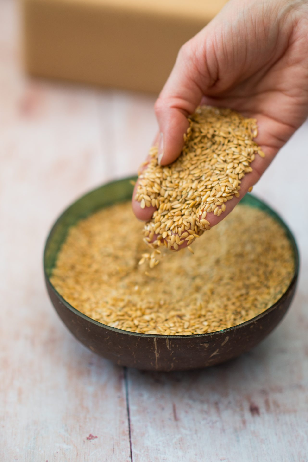 Sustainable relaxation eye pillow filling in a bowl on a wooden table with a woman's hand holding them